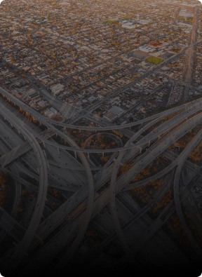 Drone aerial view of a complex urban freeway system and residential area, illustrating American Security Force's wide-area surveillance capabilities.