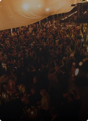 Large crowd gathered at a nighttime event under a canopy, representing crowd control and event security services by American Security Force.
