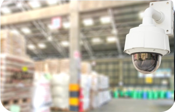 Dome surveillance camera mounted inside a warehouse with stacked goods, representing warehouse security solutions by American Security Force.