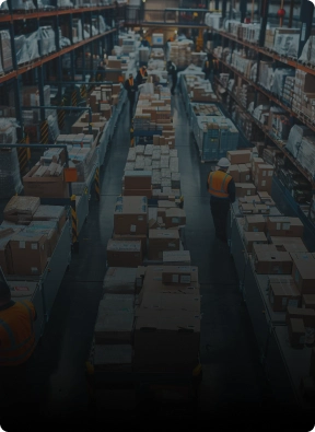 Workers managing inventory in a large warehouse with stacked boxes and high shelves, representing logistics security services by American Security Force.