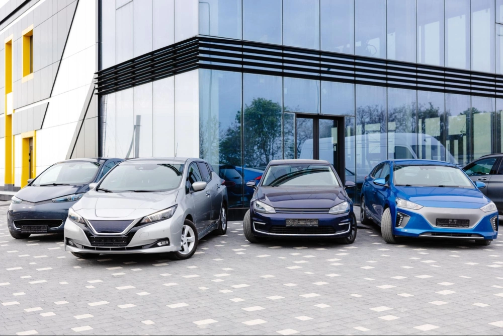 Car dealership parking lot with multiple vehicles parked outside a modern showroom, secured by American Security Force professional auto dealership security guards.