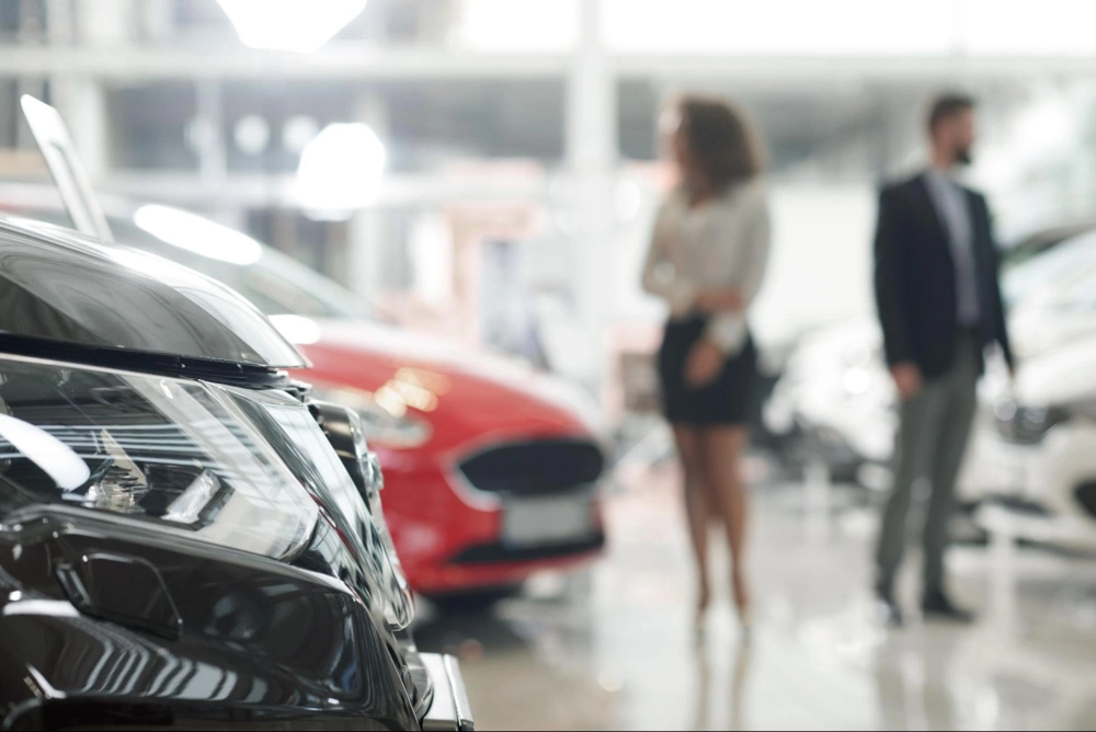 Car dealership showroom with vehicles on display and customers browsing, protected by professional car dealership security services from American Security Force.