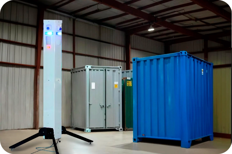 Sentinel Mobile Surveillance for Warehouse & Industrial Security A portable white Sentinel surveillance tower with glowing blue and orange lights, providing advanced security monitoring in a large warehouse setting with shipping containers, ideal for remote site security and asset protection.