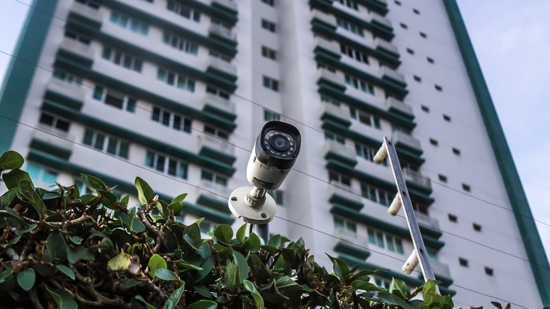 Outdoor surveillance camera mounted in front of a high-rise residential building for better property management and increased security.