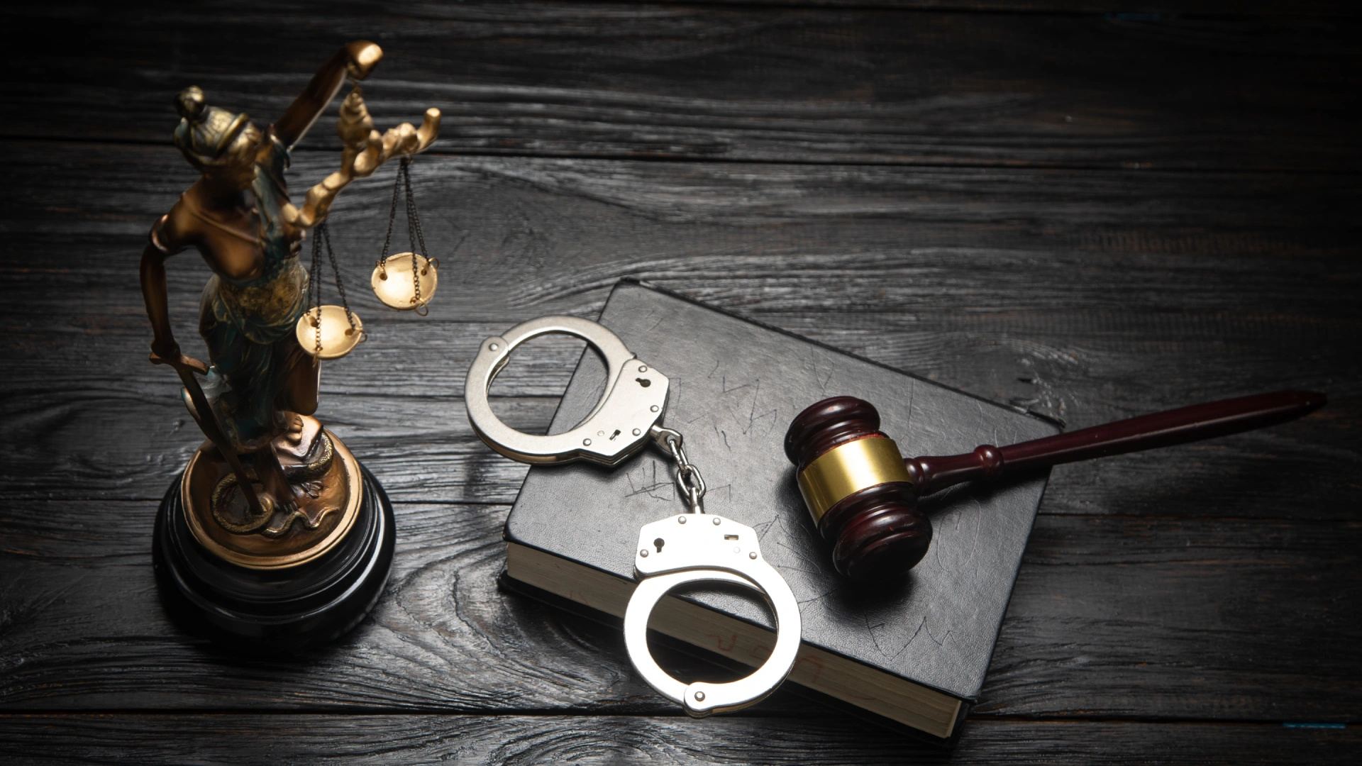 Handcuffs, gavel, and Lady Justice statue symbolizing different types of crime and the US legal system.