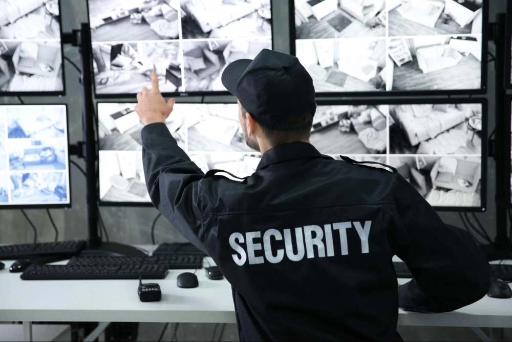 Professional security guard monitoring multiple surveillance camera feeds in a control room — representing 24/7 security monitoring solutions by American Security Force.