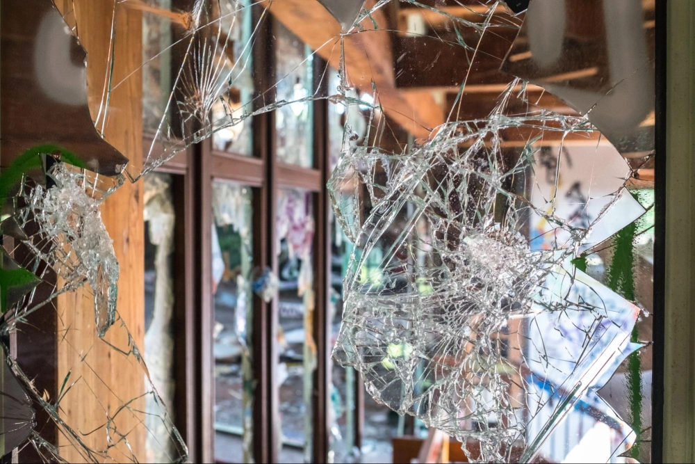 Shattered glass door after a break-in, emphasizing the need for reliable commercial property security and vandalism prevention by American Security Force.
