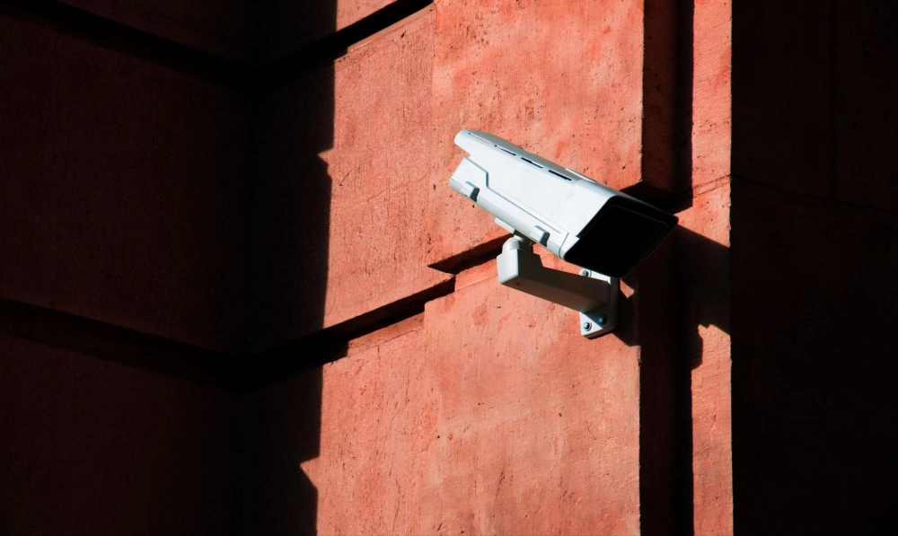 Exterior security camera installed for 24/7 surveillance by American Security Force Mounted surveillance camera on a commercial building wall, enhancing property security and monitoring