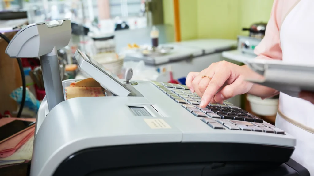 Close-up of retail employee operating cash register, illustrating employee theft risk at point of sale and the need for loss prevention strategies