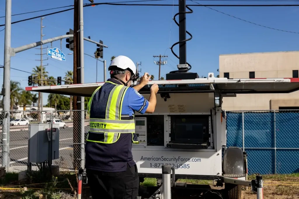American Security Force guard installing mobile surveillance trailer camera system at urban intersection in Los Angeles