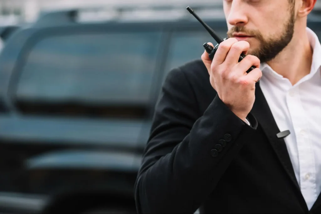 Executive protection security agent using a radio near a vehicle for American Security Force